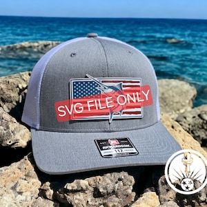 May include: A gray and white trucker hat with a red, white, and blue American flag patch featuring a marlin fish. The patch has the text "SVG FILE ONLY" on it. The hat is sitting on a pile of rocks.