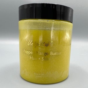 Może przedstawiać: Żółty słoik z ubijanym masłem mango do włosów i skóry. Słoik ma czarną pokrywkę, a etykieta zawiera napis "Unforgettable Whipped Mango Butter Hair Skin Made in UK 250ml".