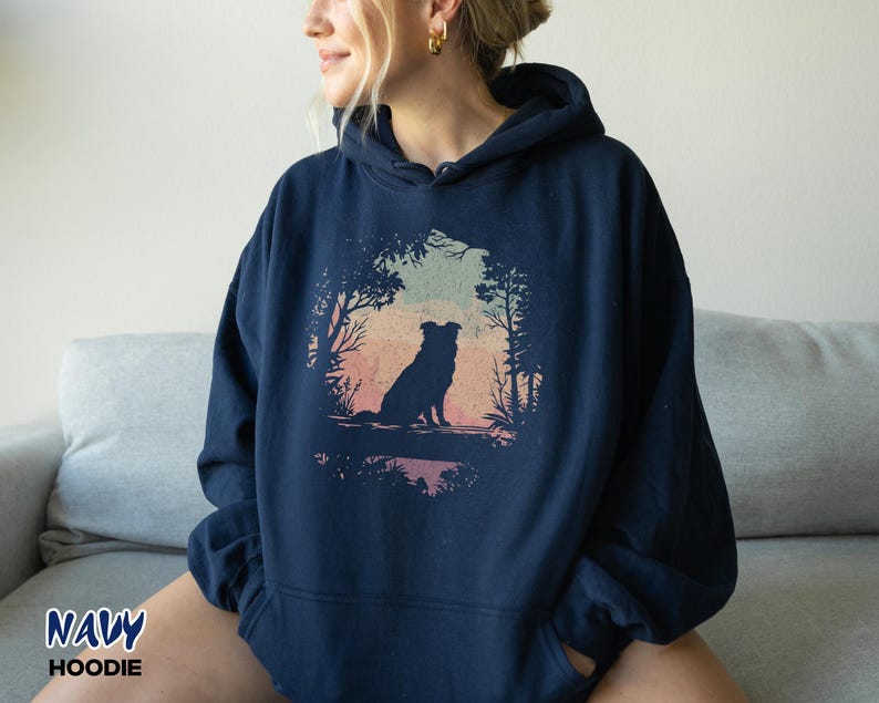 May include: Navy blue hoodie with a dog silhouette set in a natural scene, including trees and a colourful sky. The text "NAVY HOODIE" is printed at the bottom left corner of the image.