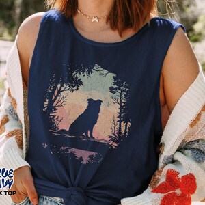 May include: A navy blue vest top featuring a circular graphic of a dog silhouette in a forest scene. The graphic shows a dog sitting, with trees and a colourful sunset background. The text "TRUE NAVY TANK TOP" is printed on the bottom left.
