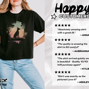 Pu&ograve; includere: T-shirt nero ampio con la silhouette di un cane in una scena di foresta con tonalit&agrave; colorate. La maglietta ha la scritta "BLACK BOXY TEE" in basso. L'immagine include anche recensioni dei clienti.