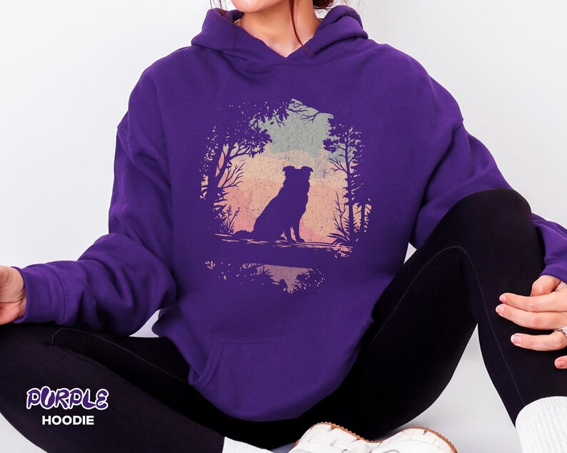 May include: A purple hooded sweatshirt with a dog silhouette in a forest scene against a sunset. The text "PURPLE HOODIE" is at the bottom left of the image.