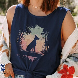 Pu&ograve; includere: Canotta blu navy con la silhouette di un cane in una scena di foresta. La grafica presenta un cane seduto in una foresta con uno sfondo colorato del tramonto. Il testo "TRUE NAVY TANK TOP" &egrave; stampato in basso a sinistra.