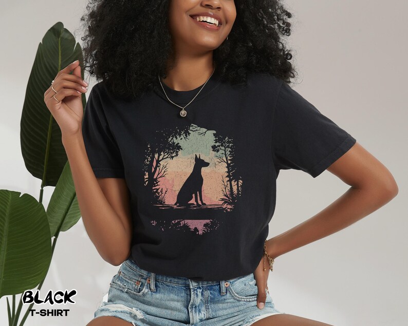 Pu&ograve; includere: T-shirt nero con la silhouette di un cane in una scena di foresta con una tavolozza di colori al tramonto. Il testo "BLACK T-SHIRT" &egrave; stampato in basso a sinistra. La maglietta &egrave; realizzata in un materiale morbido.