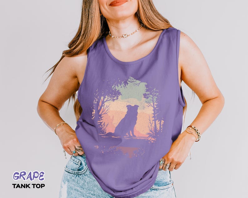 May include: A sleeveless grape-coloured tank top with a dog silhouette set against a sunset landscape. The text "GRAPE TANK TOP" is printed at the bottom. The tank top is made of a soft material and is suitable for warm weather.