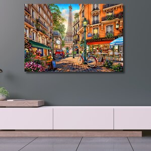 May include: A colourful painting depicting a Parisian street scene with a flower shop, a bakery called "Boulanger Patissier", and a bicycle. The Eiffel Tower can be seen in the background.