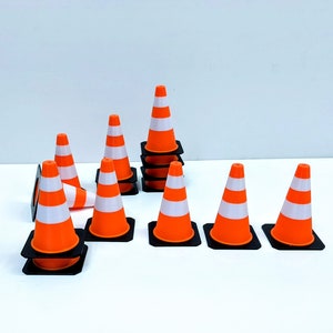 Könnte beinhalten: Ein Satz von zehn orangefarbenen und weißen Verkehrskegeln mit schwarzen Basen. Die Kegel sind in einem Halbkreis angeordnet, wobei ein Kegel auf einem anderen gestapelt ist.