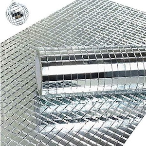 May include: A roll of silver mosaic tile sits atop a sheet of the same tile, with a disco ball in the background. The tiles are small squares, reflecting light. This decorative tile is suitable for various craft projects.