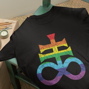 May include: A black t-shirt with a rainbow colored symbol, resembling a cross and an infinity sign, printed on the front. The symbol has a distressed, vintage look.