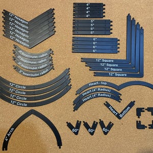以下が含まれることがあります： 六角形、正方形、円、アーチなど、黒いプラスチック製の建設用部品のコレクション。4インチ、5インチ、6インチ、12インチなど、さまざまなサイズがインチで表示されています。「Heart」と「60°」とラベル付けされた部品もあります。