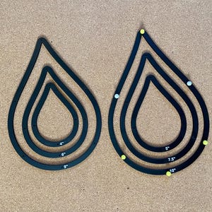 May include: Two sets of black teardrop-shaped stencils with four different sizes. The stencils are labeled with measurements in inches: 4", 6", 9", 5", 7.5", and 10".
