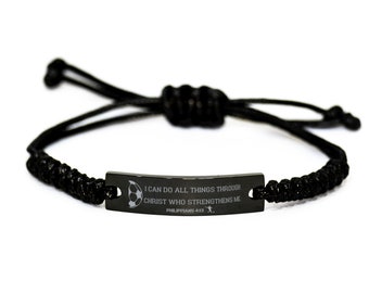 Op de afbeelding: Een verstelbare zwarte koordarmband met een centrale matzwarte metalen balk gegraveerd met een voetbalicoon, een silhouet van een voetballer en de tekst I CAN DO ALL THINGS THROUGH CHRIST WHO STRENGTHENS ME PHILIPPIANS 4:13.
