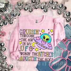 May include: Pink sweatshirt with a graphic of a cartoon alien in a UFO with the text "Cruisin' through the air in my UFO,  Robbin' the Bitches Abductin' the Hoes".