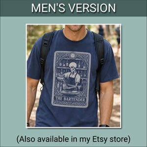 May include: A graphite-coloured short-sleeve t-shirt featuring a graphic print of a skeleton bartender working behind a bar. The design is framed like a tarot card with the text THE BARTENDER at the bottom. The shirt has a crew neckline and a relaxed fit.