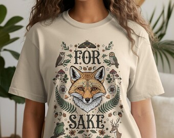 Op de afbeelding: Ivoor kleurig t-shirt met een gedetailleerde illustratie van een vossengezicht omringd door bos elementen. De tekst "FOR SAKE" is boven en onder de vos gebogen. Het ontwerp bevat uilen, paddenstoelen en een hert.