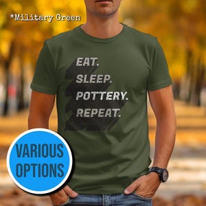 May include: A green t-shirt with the text "Eat. Sleep. Pottery. Repeat." printed on it. The text is in a white, distressed font. The shirt is being modelled by a person.