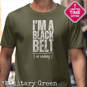 May include: A green t-shirt with the text "I'M A BLACK BELT (in coding)" printed in white. The text has a distressed, vintage look.