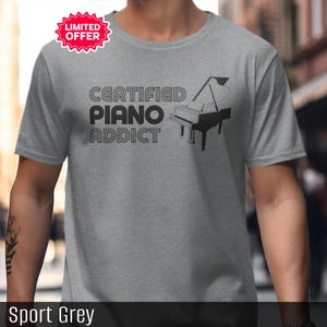May include: Sport grey t-shirt with the text "CERTIFIED PIANO ADDICT" and a black piano graphic. A red and white "LIMITED OFFER" sticker is in the upper left corner. The shirt is made of a soft material.