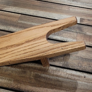 May include: A wooden boot jack with a natural wood finish. The boot jack is designed to help remove boots easily.
