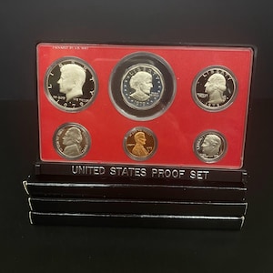 Op de afbeelding: Een 1979 United States Proof Set in een rood en zwart etui. De set bevat zes munten, waaronder een Kennedy half dollar, een kwart dollar, een dime, een nickel en een penny. De tekst "PACKAGED BY U.S. MINT" is zichtbaar.