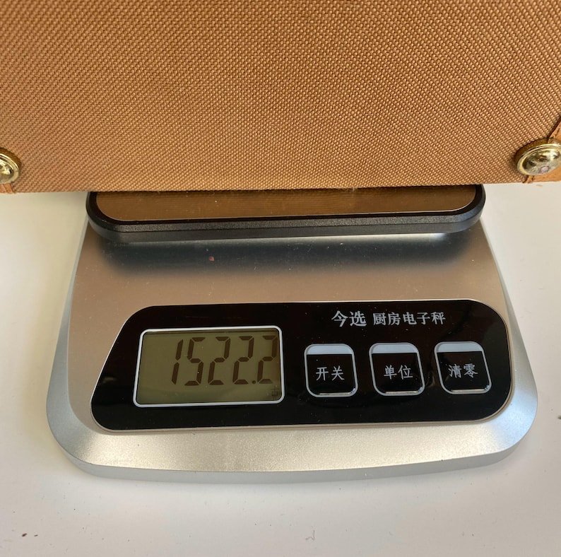 May include: A brown bag is placed on a digital kitchen scale. The scale displays a weight of 1522.2. The scale has a black display with Chinese characters and buttons.