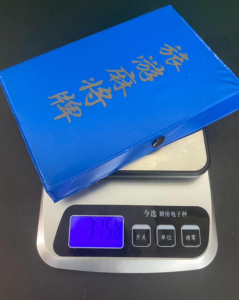 Puede incluir: Una caja azul de fichas de Mahjong con letras doradas descansa sobre una b&aacute;scula de cocina digital. La b&aacute;scula muestra un peso de 375,8. La b&aacute;scula tiene botones con caracteres chinos.