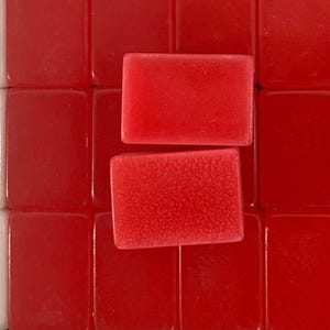 Puede incluir: Primer plano de fichas de Mahjong rojas. Dos fichas con superficie texturizada est&aacute;n enfocadas. Las otras fichas son lisas y brillantes. Se ven algunas fichas blancas con dise&ntilde;os florales.