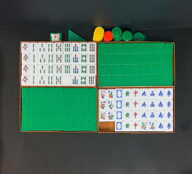 May include: A Mahjong set, featuring white tiles with symbols and characters, stored in a brown box with green compartments. Includes coloured chips and dice. A traditional board game.
