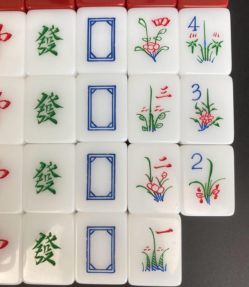 May include: A collection of white Mahjong tiles with various symbols and characters. Some tiles feature green Chinese characters, blue rectangles, and red and green floral designs. Numbers 2, 3, and 4 are also visible on some tiles.