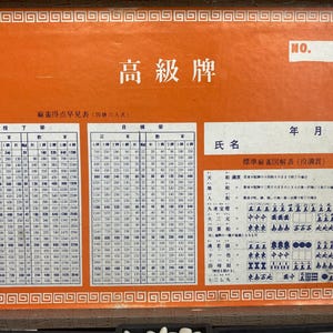 May include: An orange Mahjong scoring chart with Japanese text and a decorative border. The chart includes tables of numbers and characters, with the words "NO." and "高級牌" visible.