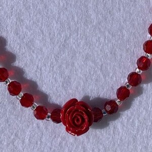 May include: A red beaded necklace with a red rose charm.