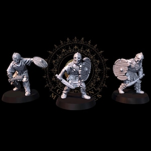 May include: Three miniature figurines of armored warriors. Each figure is posed with a shield and sword, ready for battle. The warriors wear helmets and armor, standing on black bases. The figures are in a neutral color, with a detailed design.