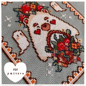 Puede incluir: Patr&oacute;n de punto de cruz con un oso polar blanco que lleva una corona de flores y sostiene una cesta de flores. El patr&oacute;n est&aacute; sobre un fondo gris con un borde marr&oacute;n. El texto "PDF pattern" est&aacute; en un coraz&oacute;n blanco.