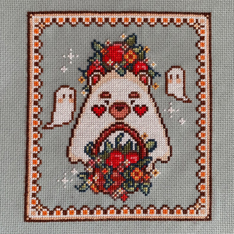 Puede incluir: Un oso blanco con corazones rojos por ojos lleva una corona de flores y sostiene una cesta de flores rojas y naranjas. Dos fantasmas blancos est&aacute;n en el fondo.