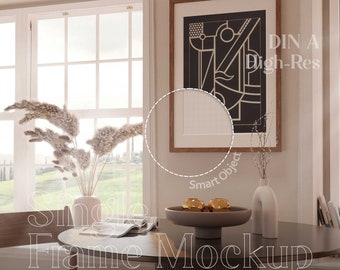 May include: A framed art print with a geometric black and white design hangs on a wall. A round table with a decorative bowl and gold spheres sits in front of the window. The text "DIN A High-Res" and "Single Frame Mockup" is visible.