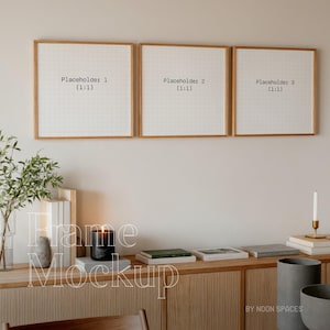 May include: Three wooden picture frames with white mounts and black text that reads "Placeholder 1 (1:1)", "Placeholder 2 (1:1)", and "Placeholder 3 (1:1)". The frames are hanging on a white wall above a wooden cabinet with a candle, books, and a vase with greenery.