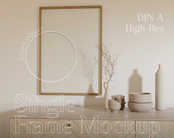 May include: A wooden frame mockup with a white background. The frame is on a wooden dresser with a light wood finish. The dresser has two drawers and a chevron pattern. The text "DIN A High-Res" is in the upper right corner of the image. The text "Single Frame Mockup" is in the lower left corner of the image. The text "BY NOON SPACES" is in the lower right corner of the image.