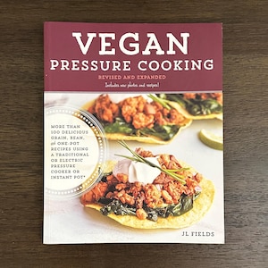 May include: A cookbook titled "VEGAN PRESSURE COOKING" with a burgundy cover. The book features recipes for grains, beans, and one-pot meals using a pressure cooker or Instant Pot. The cover displays a photo of a vegan dish.