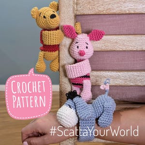 May include: Crochet pattern for Winnie the Pooh, Piglet, and Eeyore characters. The characters are crocheted in pink, yellow, and blue. The pattern is available for purchase on Etsy. #ScattaYourWorld