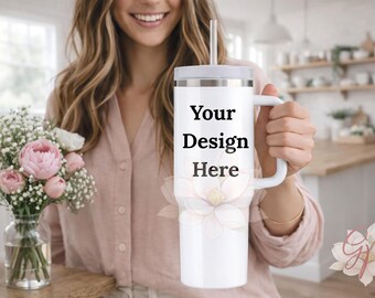 Puede incluir: Vaso blanco con asa y tapa, con el texto "Your Design Here". El vaso se sostiene frente a una persona. Un ramo de flores rosas en un jarrón de cristal está sobre una superficie de madera.