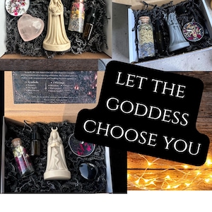 May include: Several open boxes filled with spiritual items. Each box contains a variety of items, including candles, crystals, and small bottles. The text "LET THE GODDESS CHOOSE YOU" is displayed on a black sign.