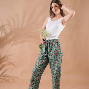 Handmade 100% cotton pajama pants for women with vibrant orange floral print on rich green fabric – breathable, soft, and lightweight lounge pants featuring elastic waistband, adjustable drawstring, and convenient pockets, perfect as relaxed fit pj pants, trendy sleep trousers, or unique menopause gift ideas and cotton anniversary gifts.