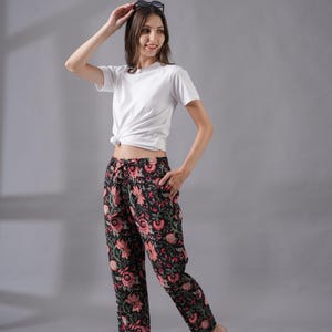 Handmade 100% cotton pajama pants for women featuring a vibrant red floral print on a black background – breathable and lightweight with soft fabric, a relaxed fit, side pockets, and an elastic waistband with drawstring, perfect as tropical boho lounge pants, modern sleepwear, or cooling pj pants ideal for menopause gift ideas and cotton anniversary gifts.