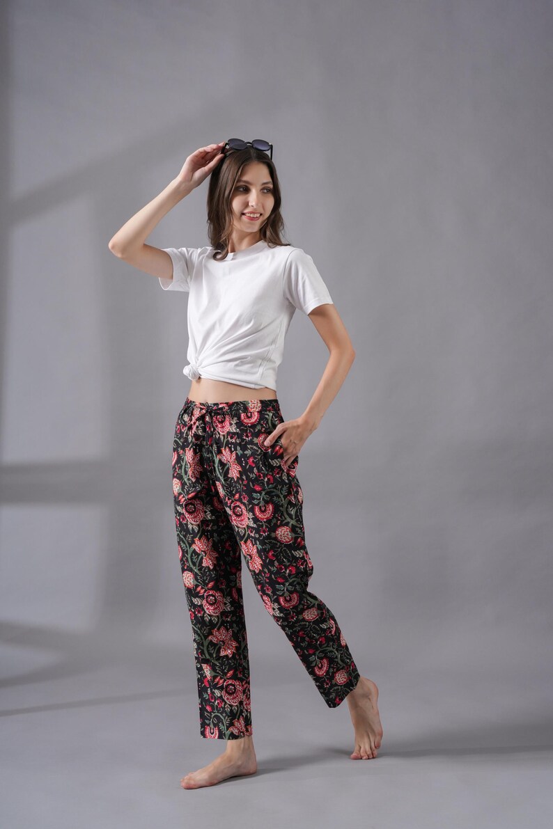 Handmade 100% cotton pajama pants for women featuring a vibrant red floral print on a black background – breathable and lightweight with soft fabric, a relaxed fit, side pockets, and an elastic waistband with drawstring, perfect as tropical boho lounge pants, modern sleepwear, or cooling pj pants ideal for menopause gift ideas and cotton anniversary gifts.
