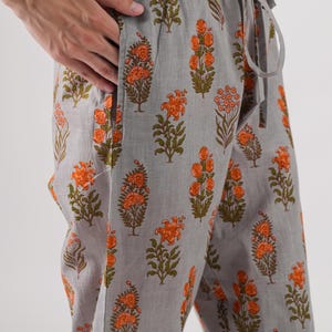 May include: Gray cotton pants with an orange floral print. The pants have an elastic waistband and a drawstring.