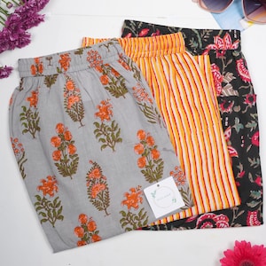 Three-pack of women’s 100% cotton pajama pants featuring bold floral and striped prints in gray, orange, black, and red – relaxed fit lounge pants with breathable, lightweight fabric, elastic waistband, drawstring, and pockets, ideal for lounge & sleepwear, cooling sleep trousers for hot nights, or modern boho jammies that make unique menopause gift ideas, gifts for flower lovers, or cotton anniversary presents.