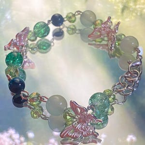May include: A silver charm bracelet with green, blue, and white beads and butterfly charms. The bracelet has a silver clasp.