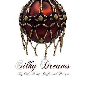 May include: A red glass Christmas ornament with a gold and black beaded design. The ornament has a beaded fringe and the text "Silky Dreams By Oak Point Crafts and Designs".