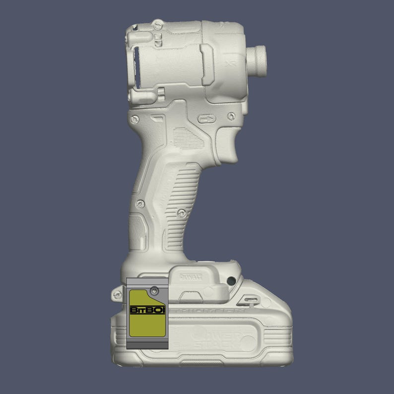 May include: A light grey cordless impact driver featuring a textured handle, a trigger mechanism, and a battery base. A rectangular yellow and grey label with the text BitBOI is attached to the side of the battery pack, which also has embossed text.