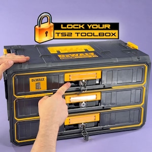 May include: A black and yellow DEWALT TS2 toolbox with three drawers, each with a lock and key. The text "LOCK YOUR TS2 TOOLBOX" is displayed above the toolbox. A finger is pointing at one of the drawer locks.